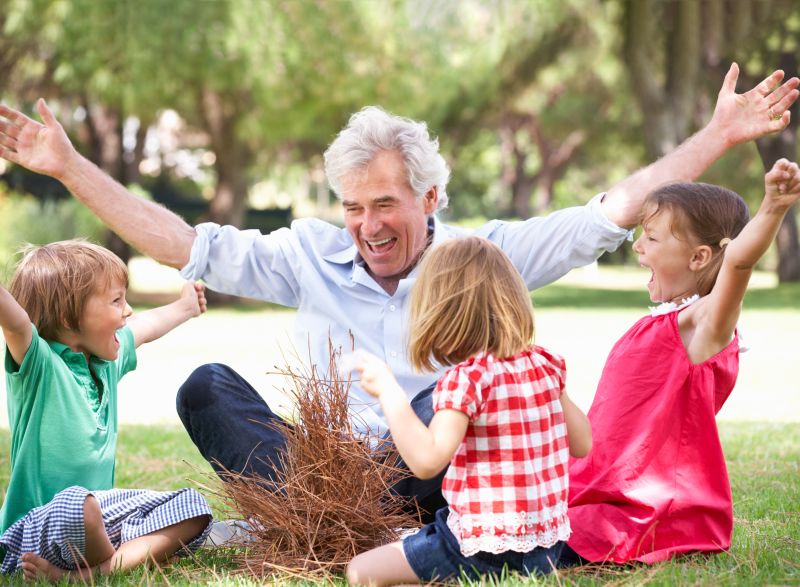 Grandfather Teaching Grandchildren To Build Camp Fire